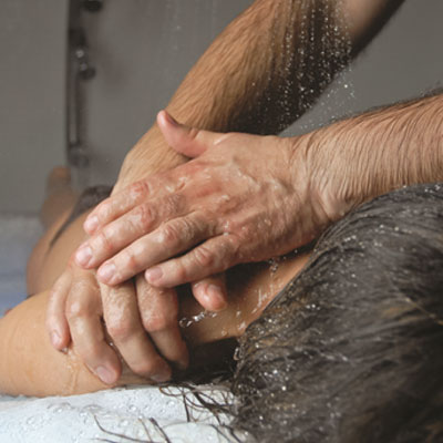 Duche que associa jatos abundantes de água termal a uma massagem manual relaxante nas costas, produzindo um efeito de descontração muscular.